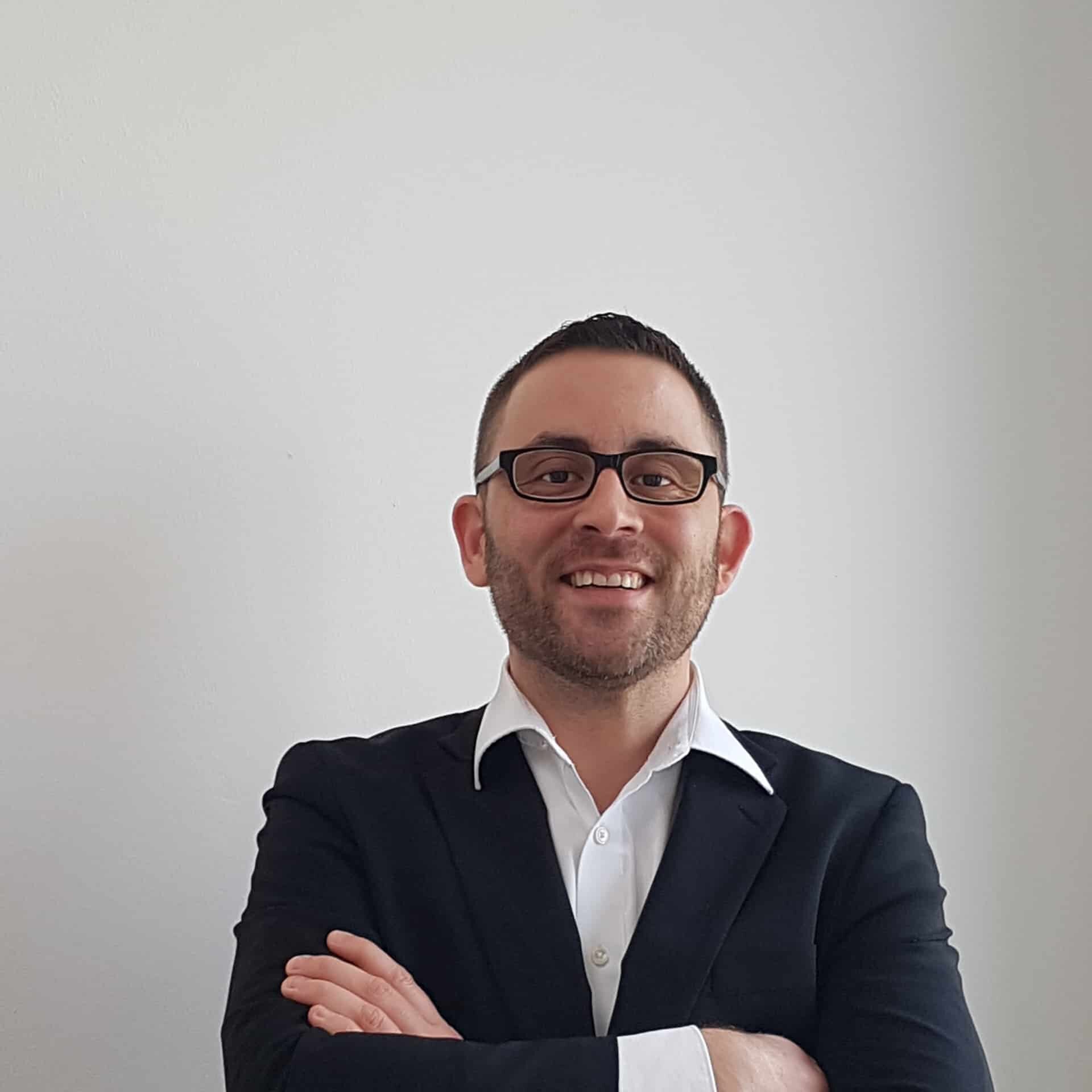 David Loebert, Diplom-Rechtswirt (FSH) und erfahrener Unternehmensberater in Karlsruhe, Heidelberg und Augsburg, in dunklem Anzug vor professionellem Hintergrund.